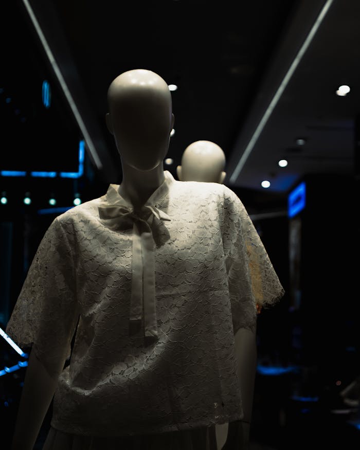 A mannequin wearing lace clothing, set in a dark, modern fashion store interior.